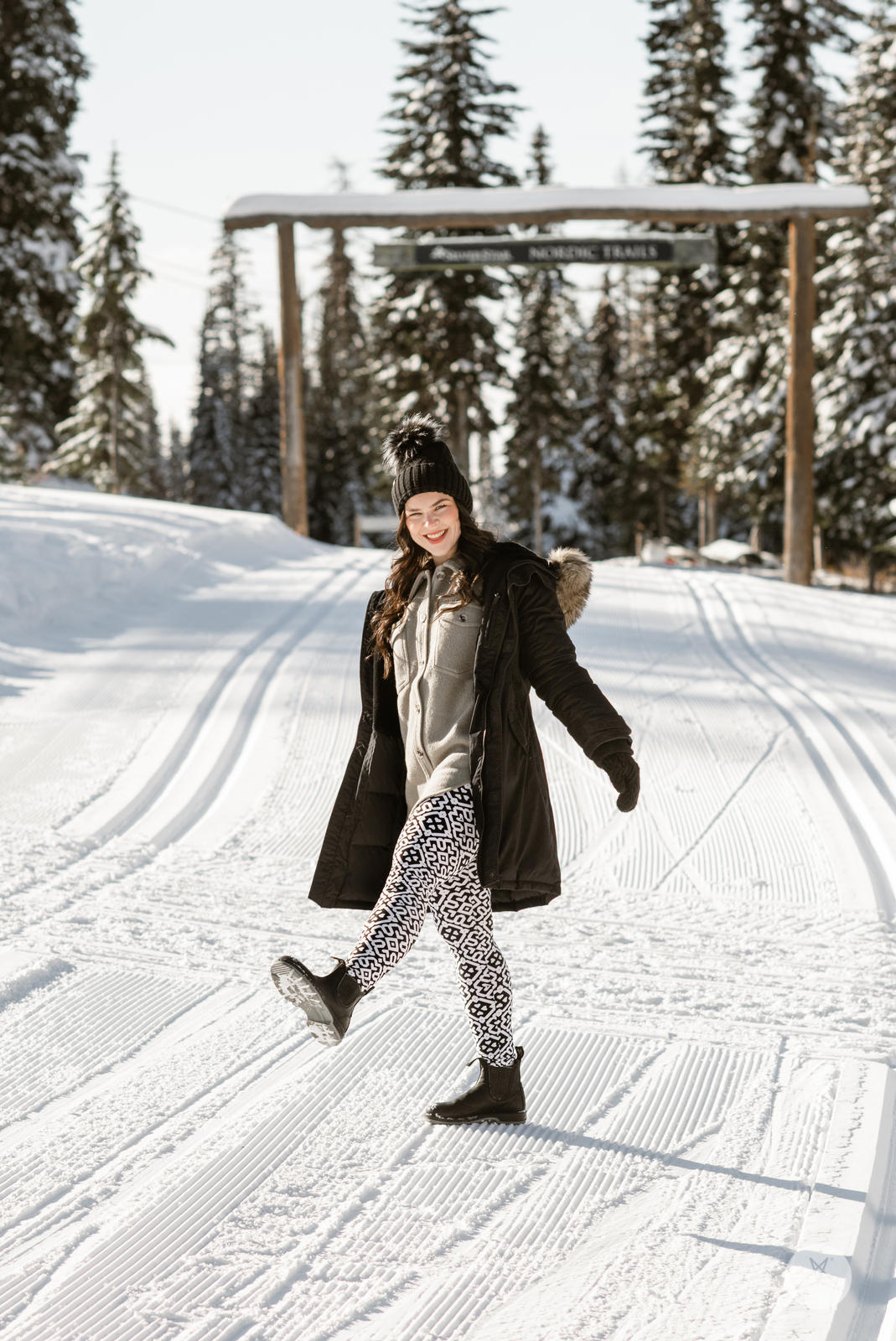 Woman in snowy landscape wearing SweetLegs Audrey leggings with black and white Moroccan geometric print and winter coat