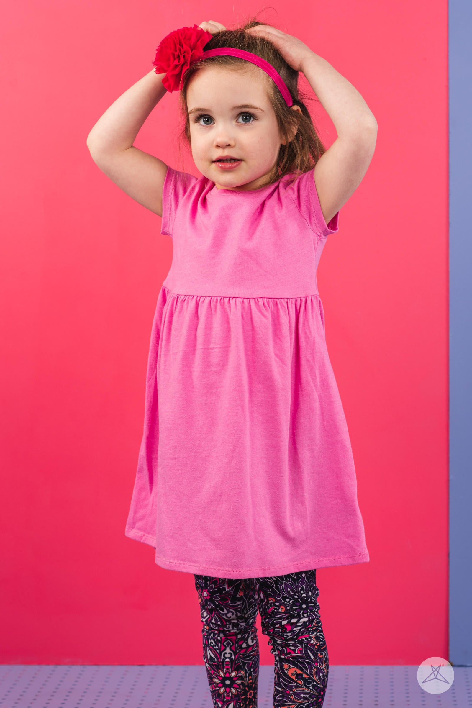 Young girl wearing SweetLegs Bohemian Beauty Kids leggings with purple and coral floral pattern against bright background