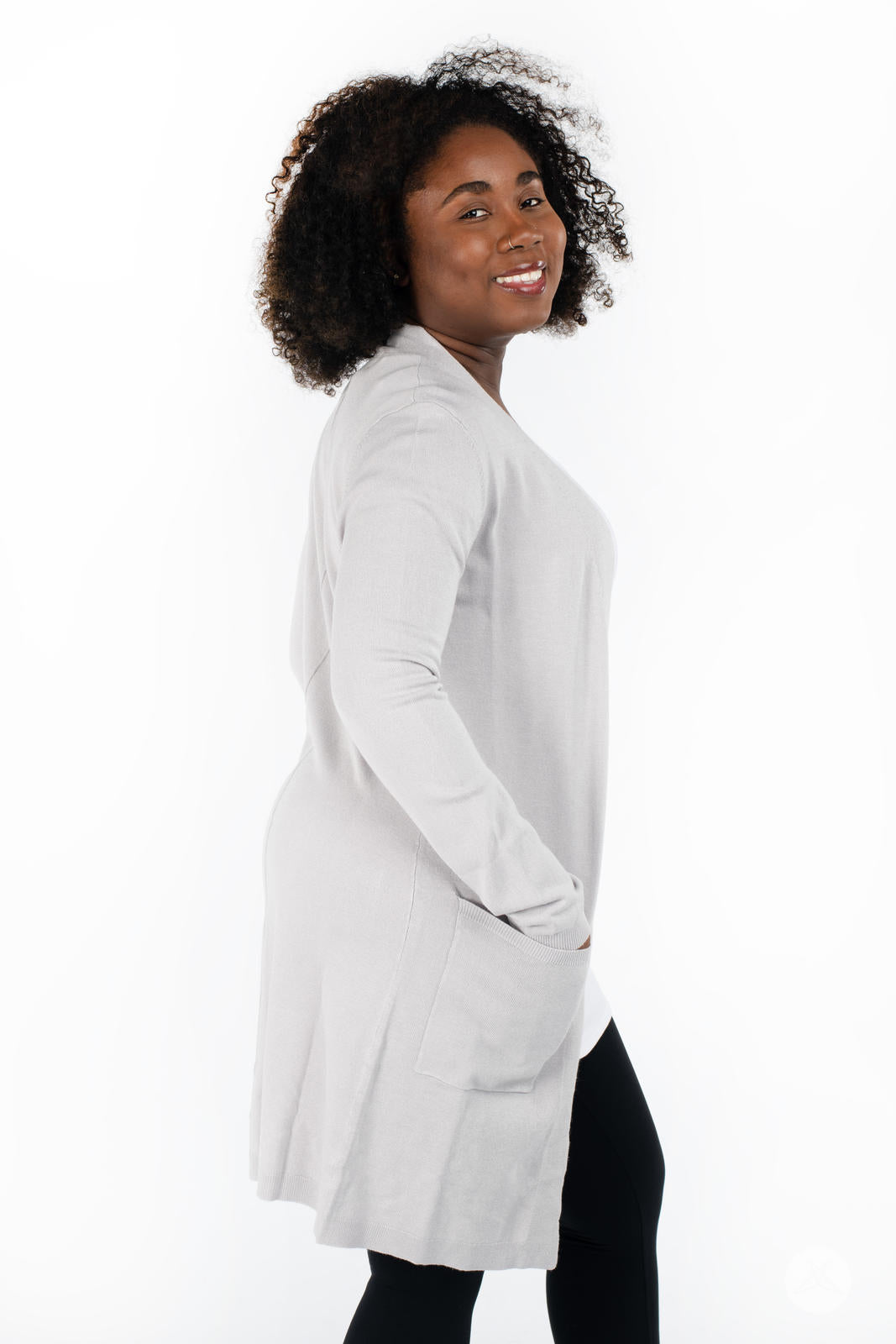 Side profile of smiling model wearing SweetLegs Canada Spring Cardigan in light grey with patch pockets and black leggings