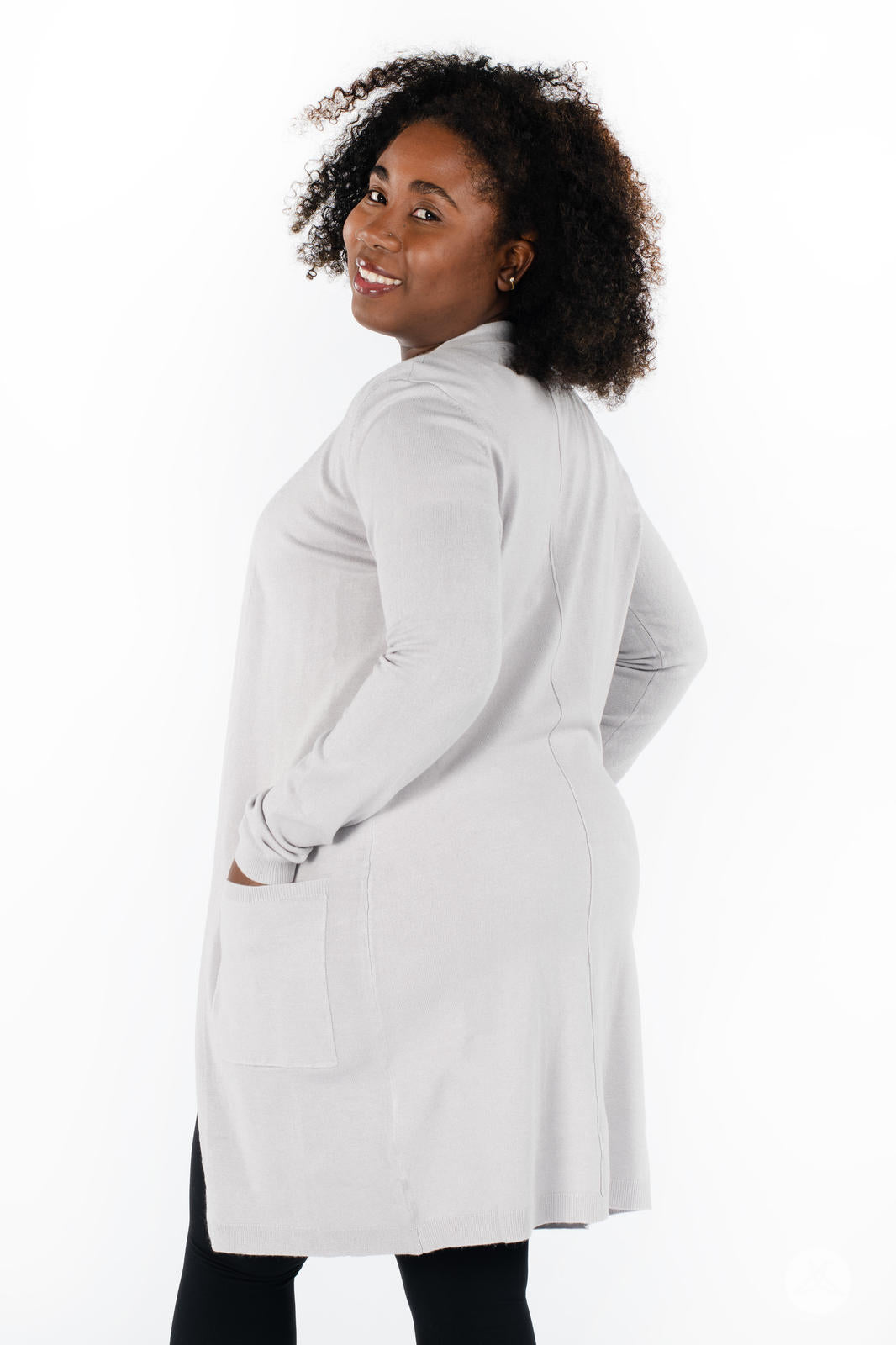 Plus-size model smiling wearing SweetLegs Canada Spring Cardigan in light grey with patch pockets back view