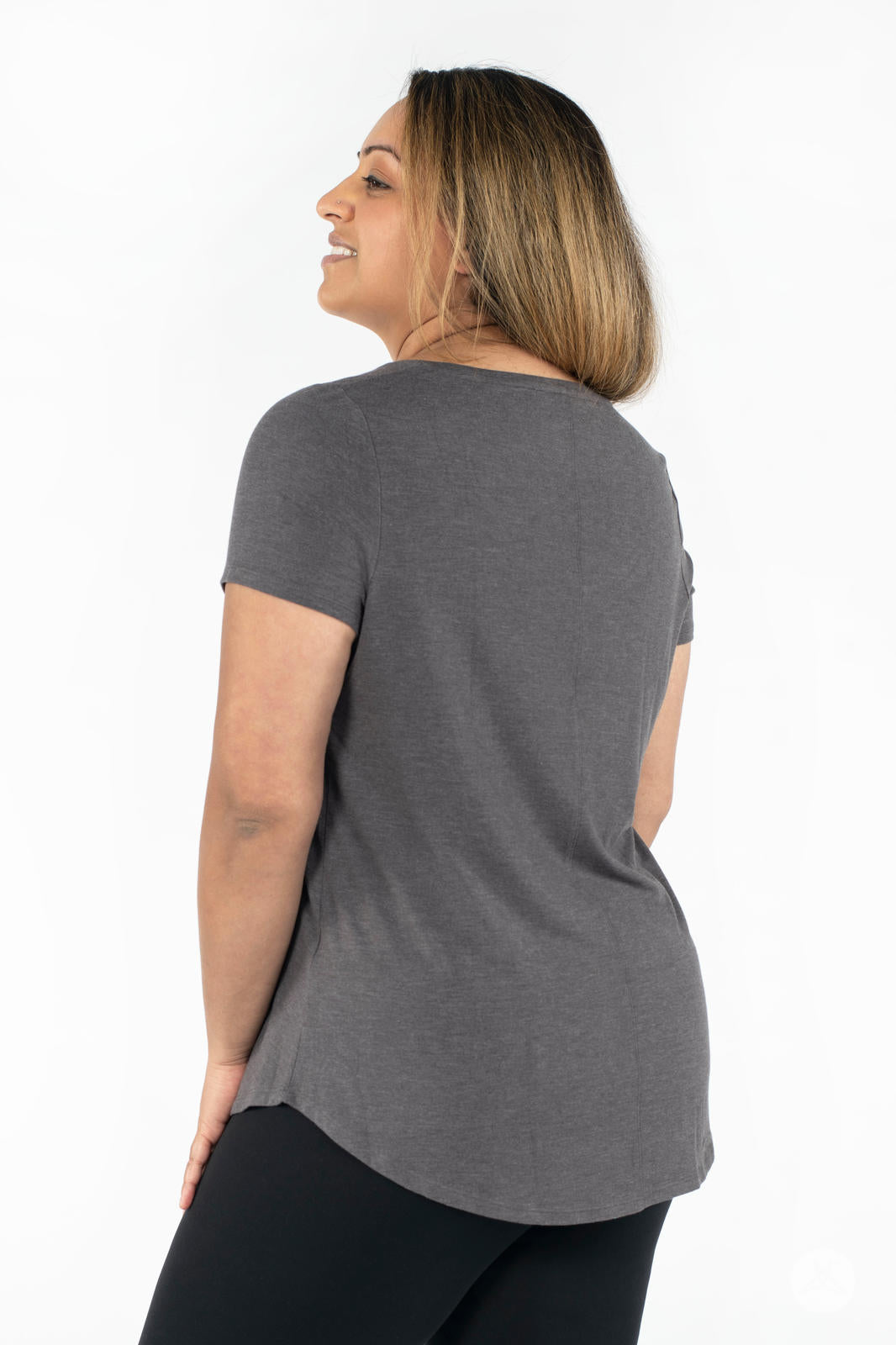 Woman wearing SweetLegs Canada Scoop Neck Tee in charcoal with short sleeves and curved hem back view smiling
