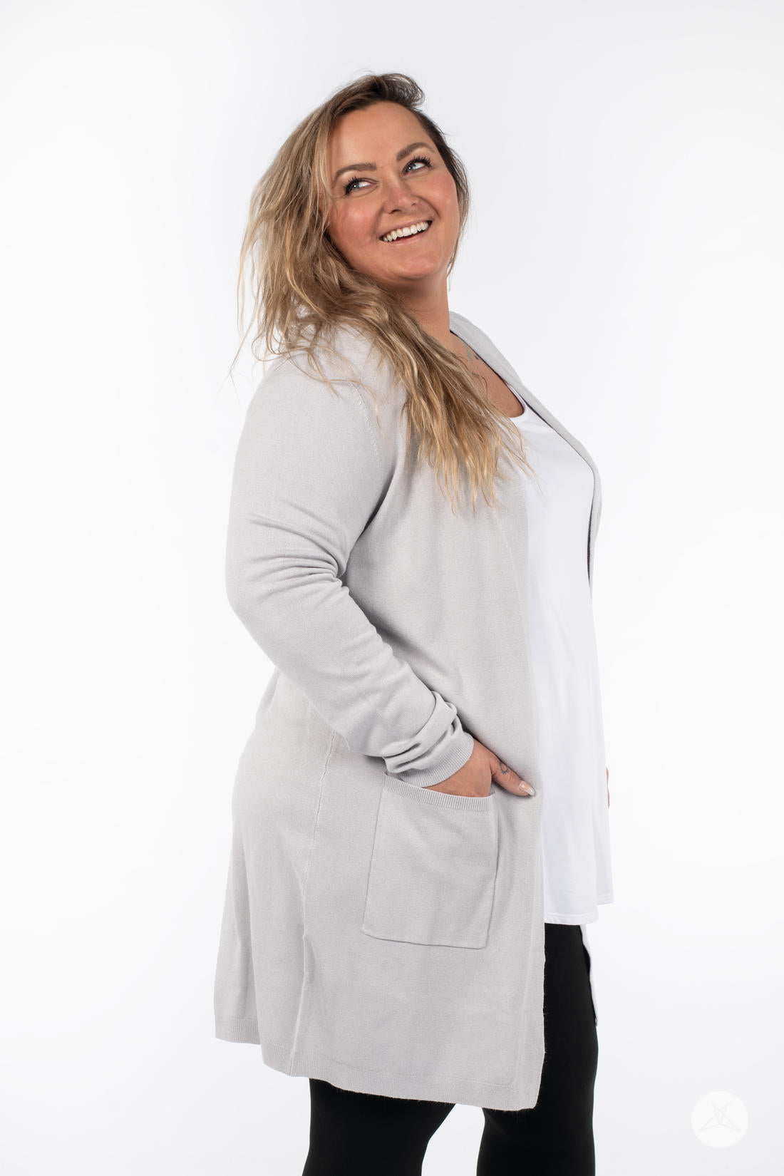 Smiling woman wearing SweetLegs Canada Spring Cardigan in light grey with patch pockets and black pants side view