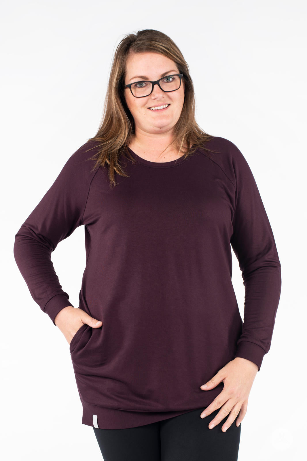 Front view of SweetLegs Canada Everyday Raglan Pullover in deep plum worn by smiling model with hands in pockets