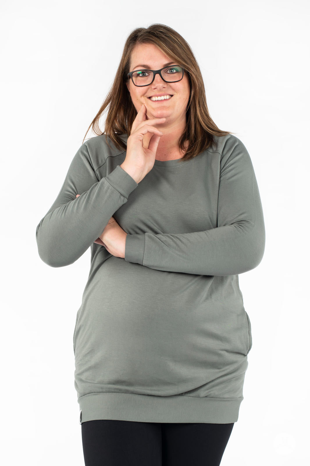 Woman smiling wearing SweetLegs Canada Everyday Raglan Pullover in muted green with hand near face and crossed arms