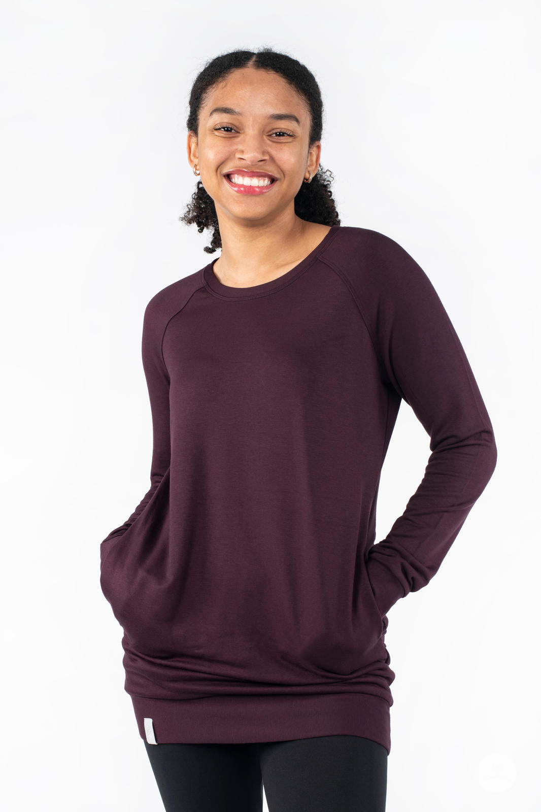 Front view of SweetLegs Canada Everyday Raglan Pullover in rich plum worn by smiling model with hands in pockets