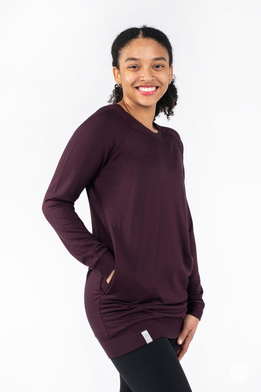 Side view of SweetLegs Canada Everyday Raglan Pullover in deep plum worn by smiling model with hands in pockets