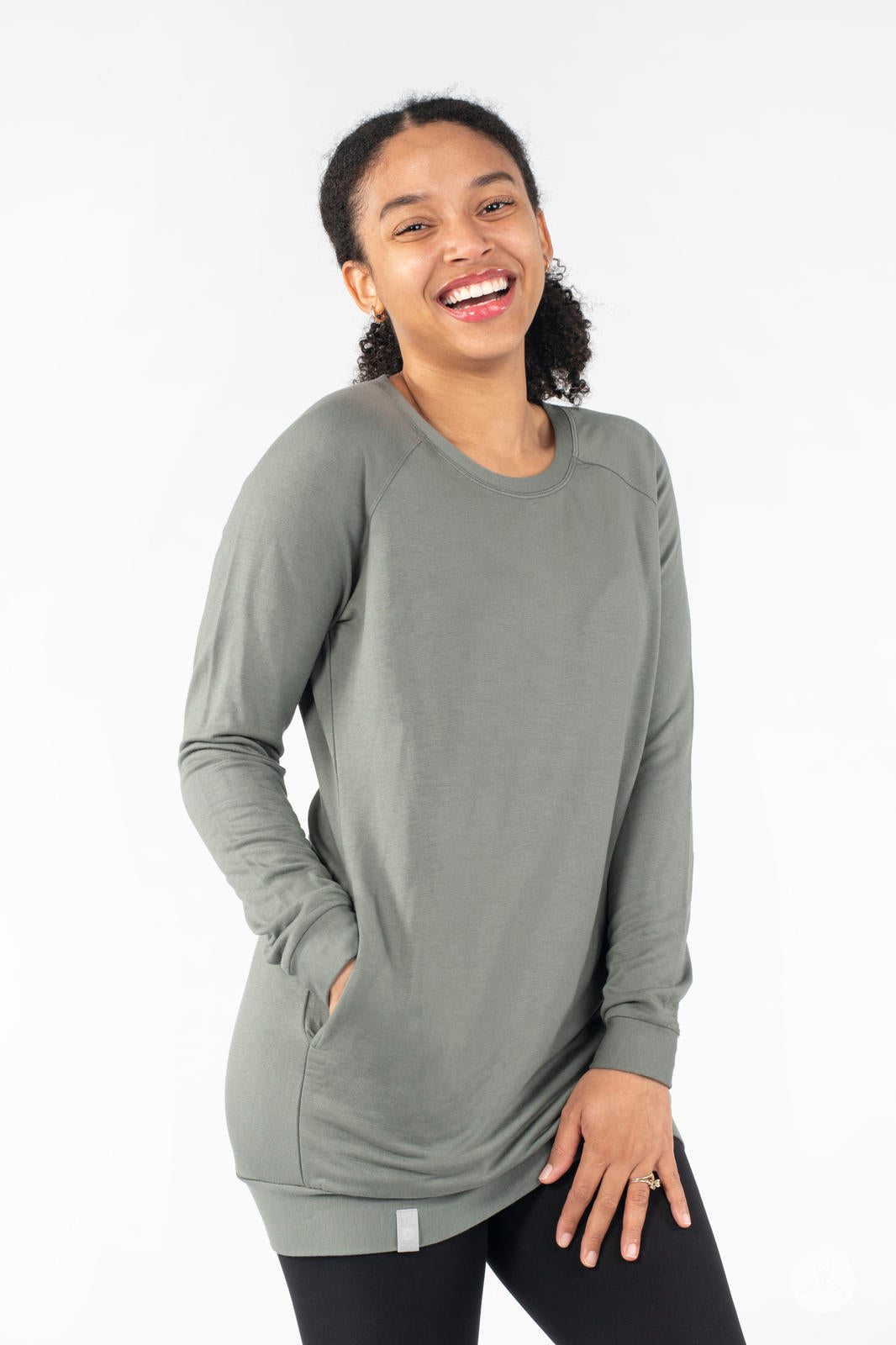 Woman smiling wearing SweetLegs Canada Everyday Raglan Pullover in muted green with hands in pockets and relaxed stance