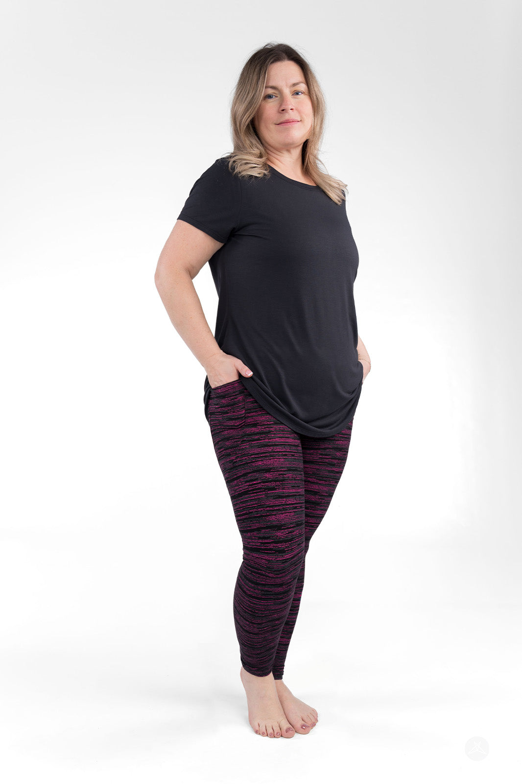 Woman wearing sweetlegs Berry Opal Pocket Leggings standing barefoot with hands in pockets against a white background