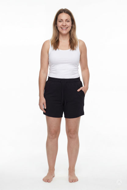 Smiling woman wearing black Lounge Shorts by SweetLegs with pockets and drawstring waist on plain white background