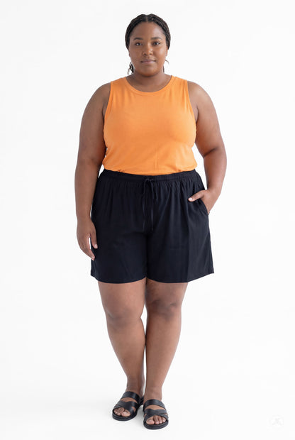 Plus size model wearing black Breeze Shorts by SweetLegs with elastic waistband and pockets, paired with orange sleeveless top