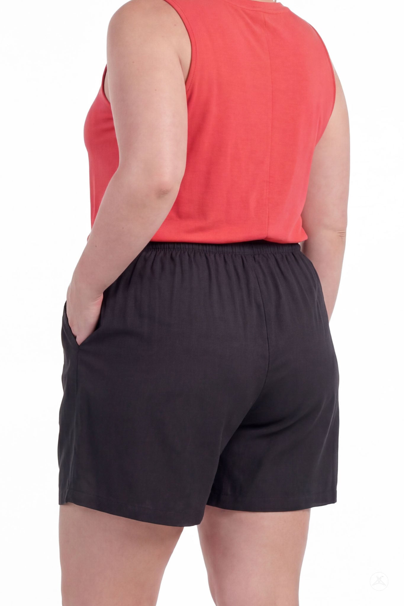 Woman wearing black Breeze Shorts by SweetLegs with elastic waistband and side pockets, back view, paired with coral sleeveless top