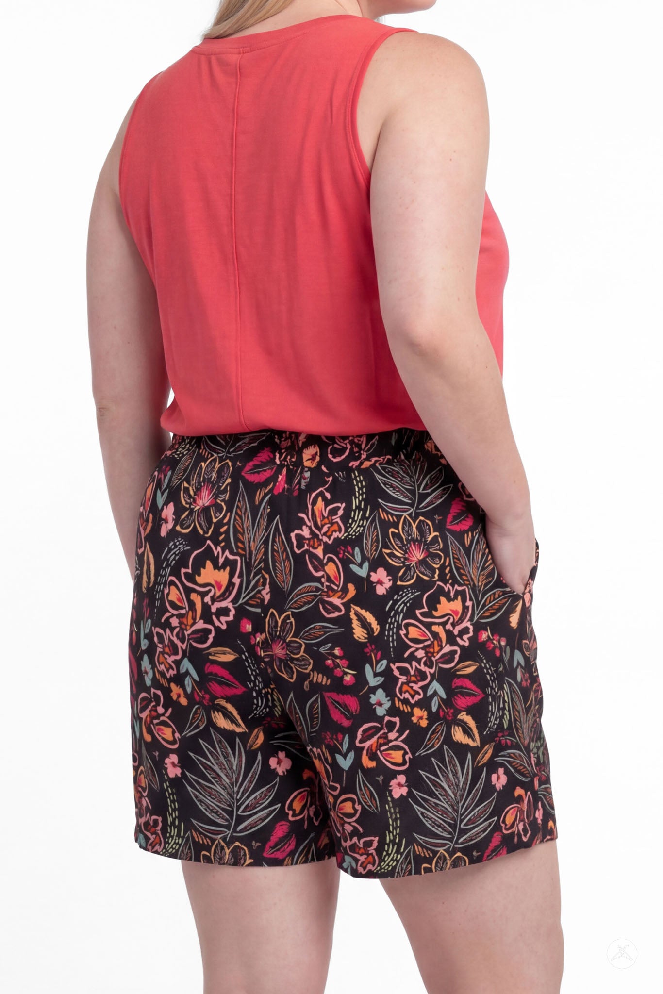 Woman wearing SweetLegs Breeze Shorts with floral print and coral sleeveless top, back view with hands in pockets