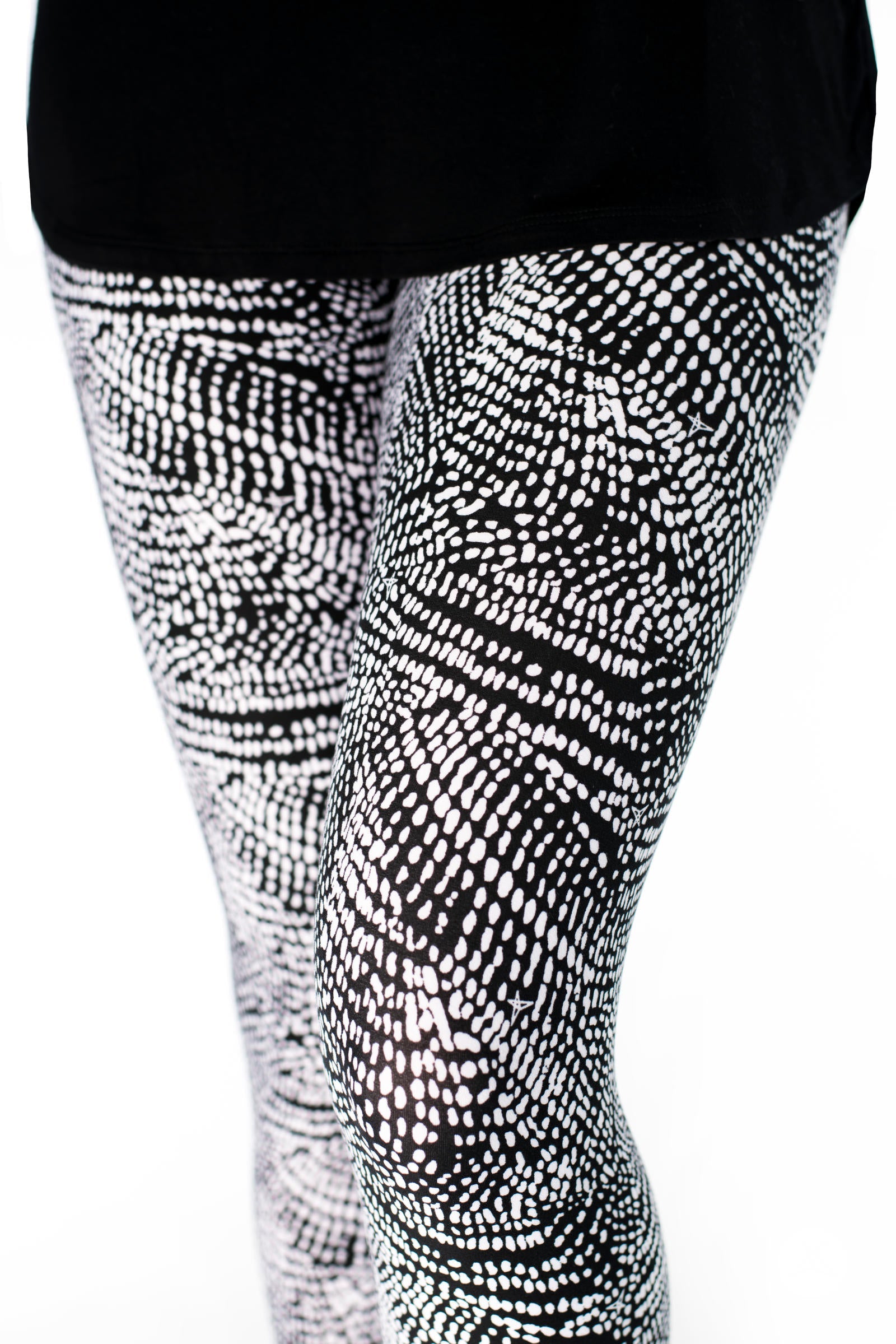 Close-up of SweetLegs Charmed leggings in black and white abstract dot pattern on model legs