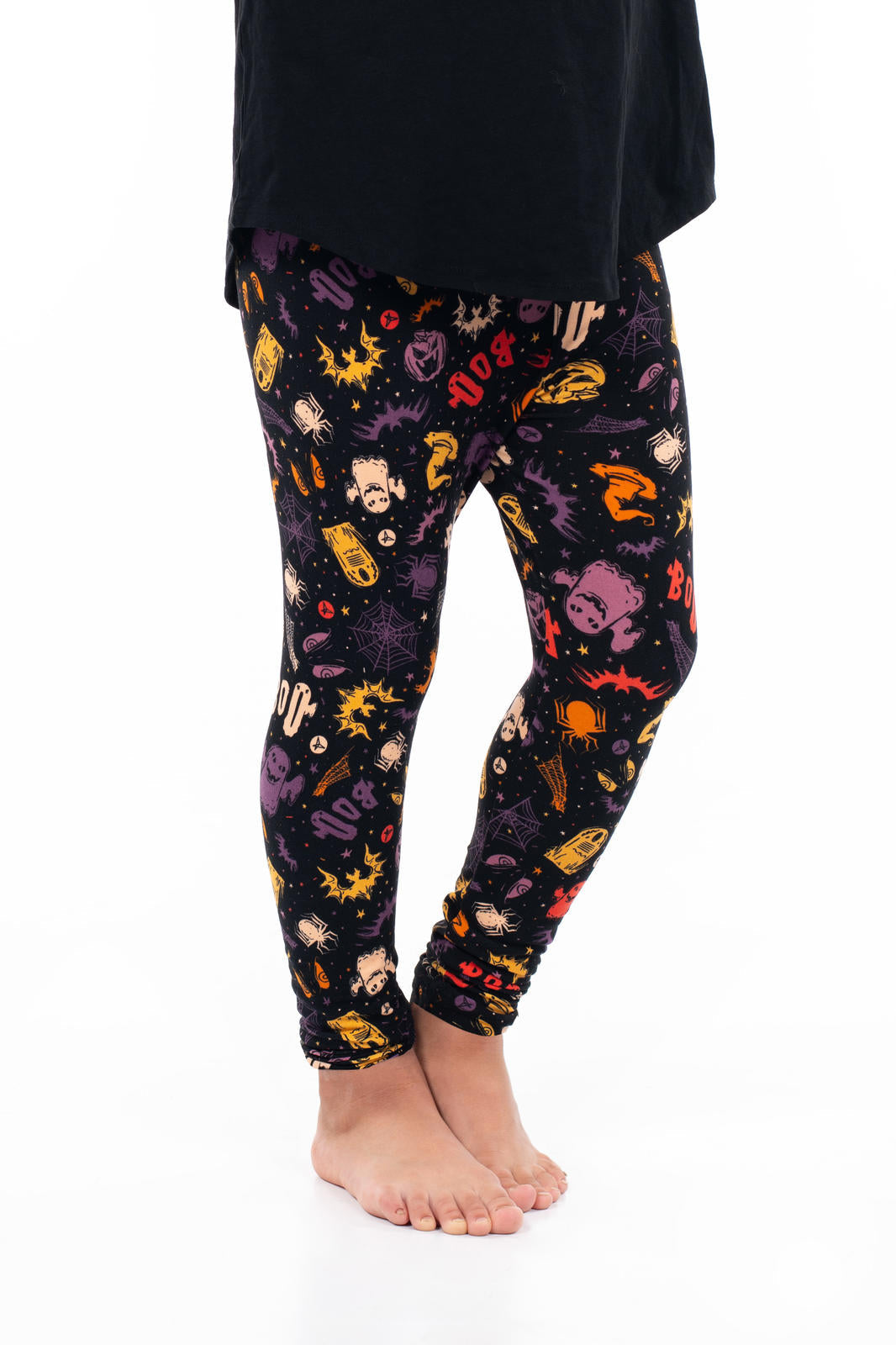 Child wearing Trick or Treat Yourself Kids leggings by SweetLegs featuring colorful Halloween prints on black background