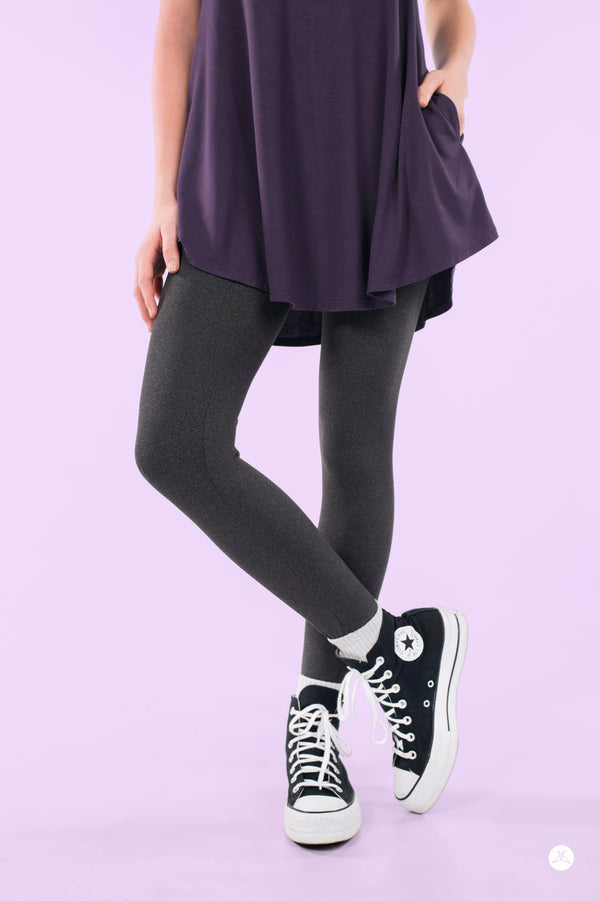 Woman wearing SweetLegs Charcoal Fade leggings with heathered texture paired with black high-top sneakers and purple top