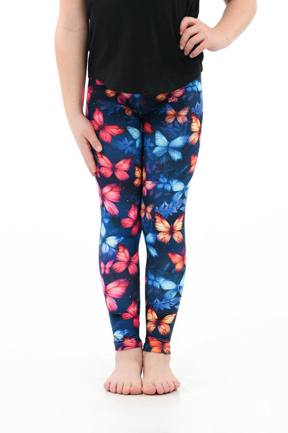 Child wearing Vault - Kids leggings by SweetLegs with vibrant red, blue, and orange butterfly pattern barefoot