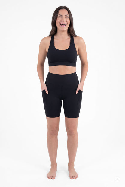Smiling woman wearing SweetLegs Black High-Waisted Pocket Biker Shorts with hands in side pockets front view
