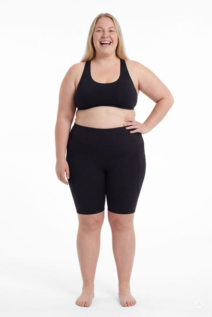 Plus size model confidently wearing SweetLegs Black High-Waisted Pocket Biker Shorts with hand on hip front view