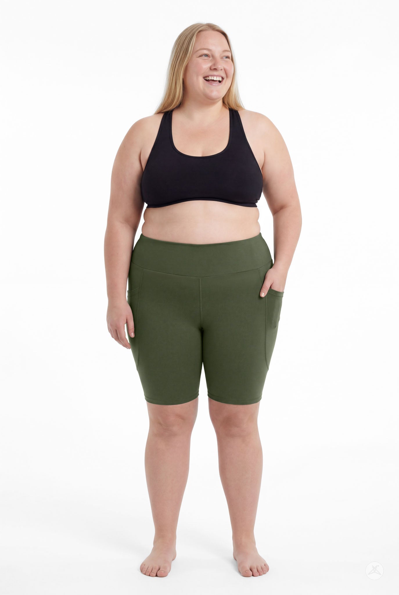Plus size woman smiling wearing SweetLegs Cedar High-Waisted Pocket Biker Shorts in green and black sports bra front view