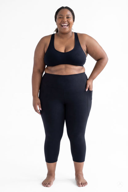 Smiling plus size woman barefoot wearing SweetLegs Black High-Waisted Pocket Crops with hand in side pocket standing front view