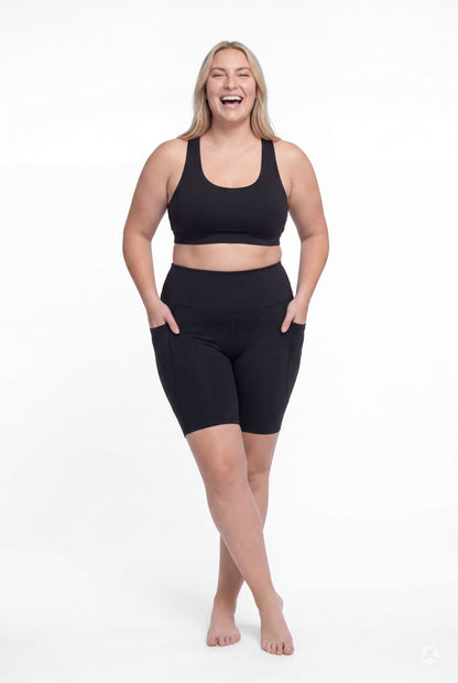 Smiling model wearing SweetLegs Black High-Waisted Pocket Biker Shorts with hands in pockets front view