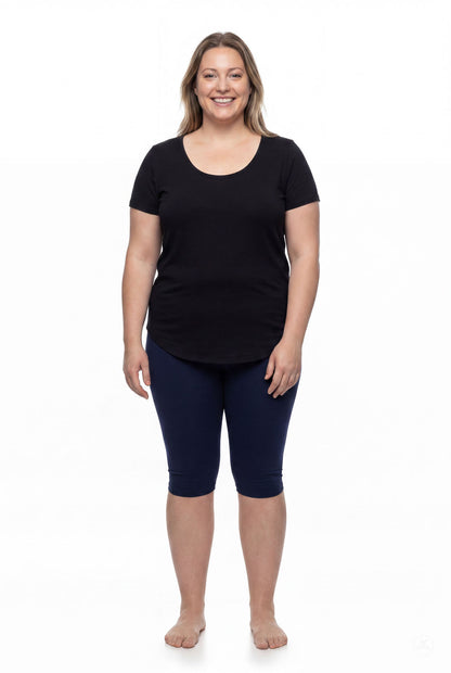 Smiling woman wearing SweetLegs Knee-Length Capri in navy blue paired with black short sleeve top barefoot on white background