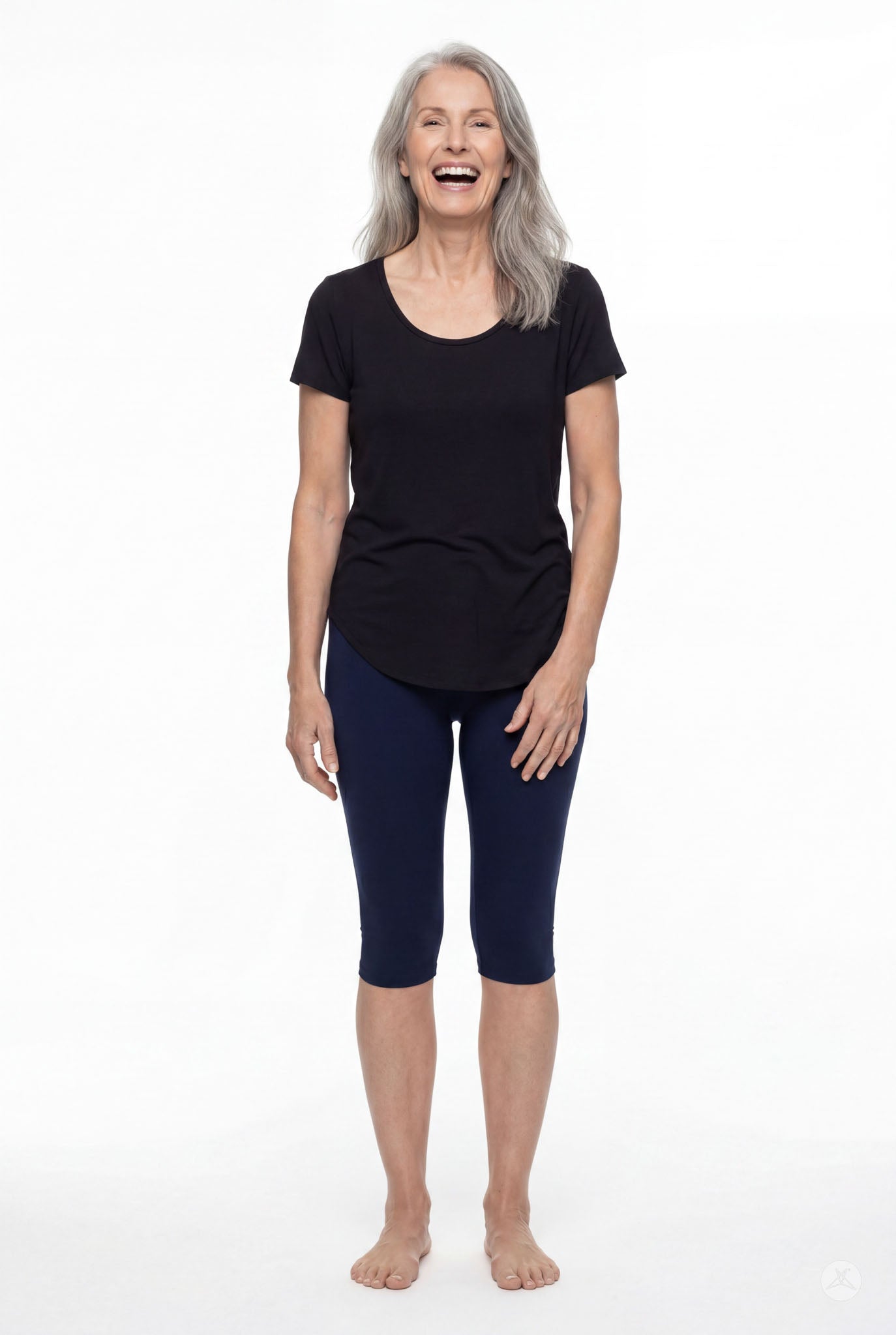 Smiling woman wearing SweetLegs Knee-Length Capri in navy blue paired with black top standing barefoot on white background