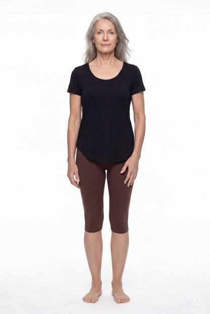 Woman wearing SweetLegs Knee-Length Capri in warm brown with black short sleeve top standing barefoot on white background
