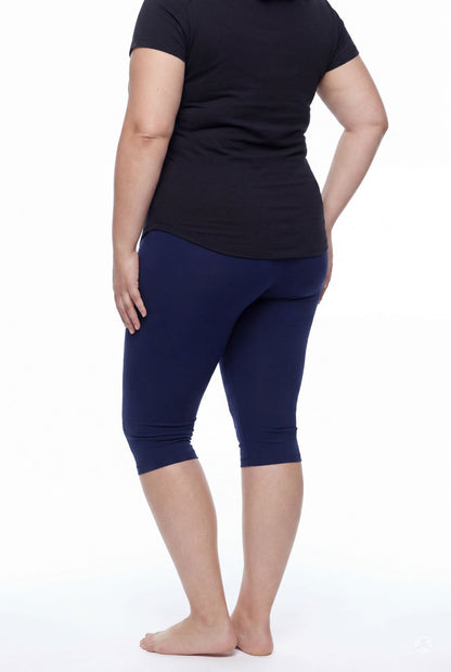 Plus size model shown from back wearing SweetLegs Knee-Length Capri in navy paired with black short sleeve top barefoot