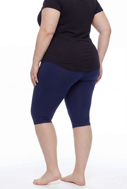 Plus size model wearing SweetLegs Knee-Length Capri in navy with black top shown from back barefoot on white background