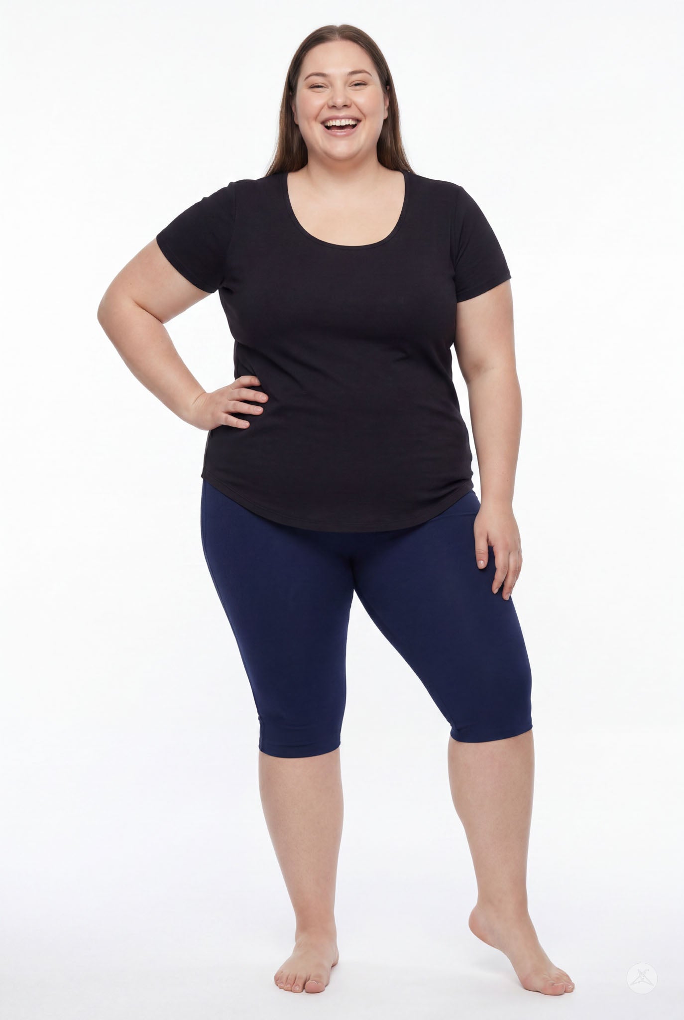Plus size model smiling wearing SweetLegs Knee-Length Capri in navy with a black short sleeve top barefoot on white background