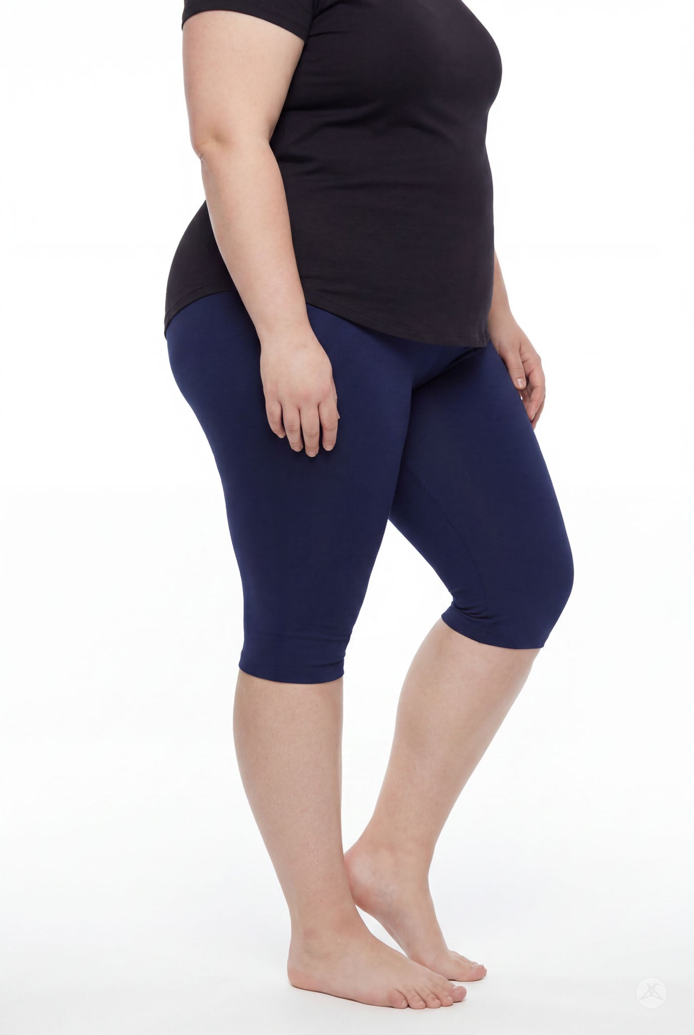 Curvy model wearing SweetLegs Knee-Length Capri in navy paired with black top standing barefoot on white background