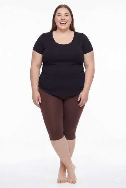 Smiling woman wearing SweetLegs Knee-Length Capri in deep brown paired with black short sleeve top barefoot on white background