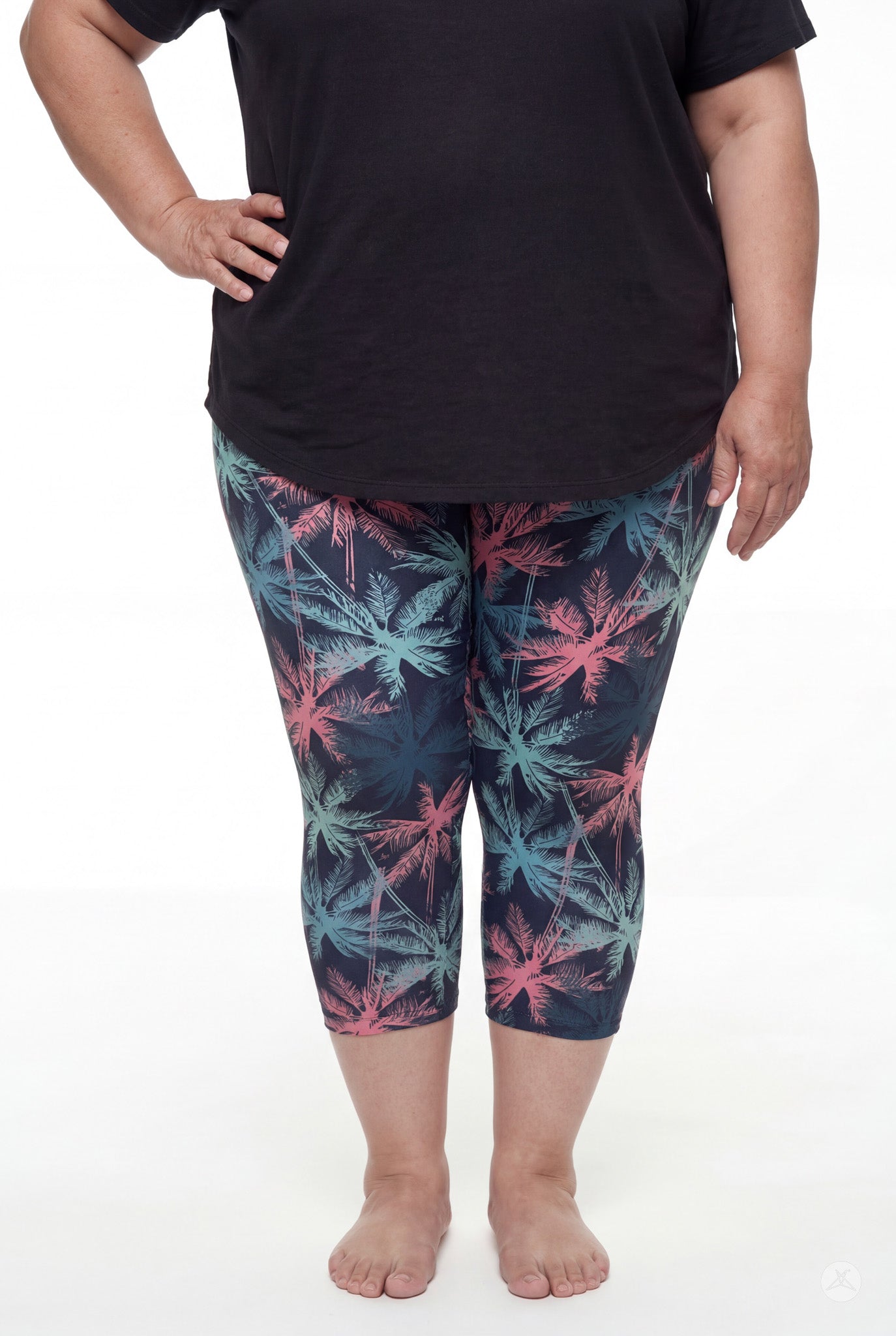 Front view of woman wearing SweetLegs Tiki Nights Crops with coral and teal palm print and black top barefoot
