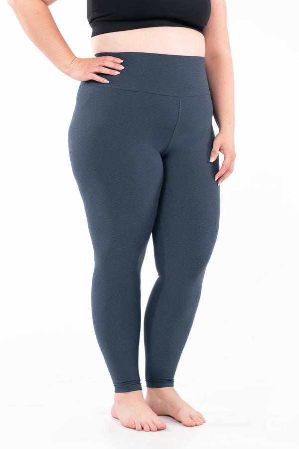Plus-size woman wearing SweetLegs Ocean Fade High-Waisted Leggings in solid heathered blue standing barefoot with black top