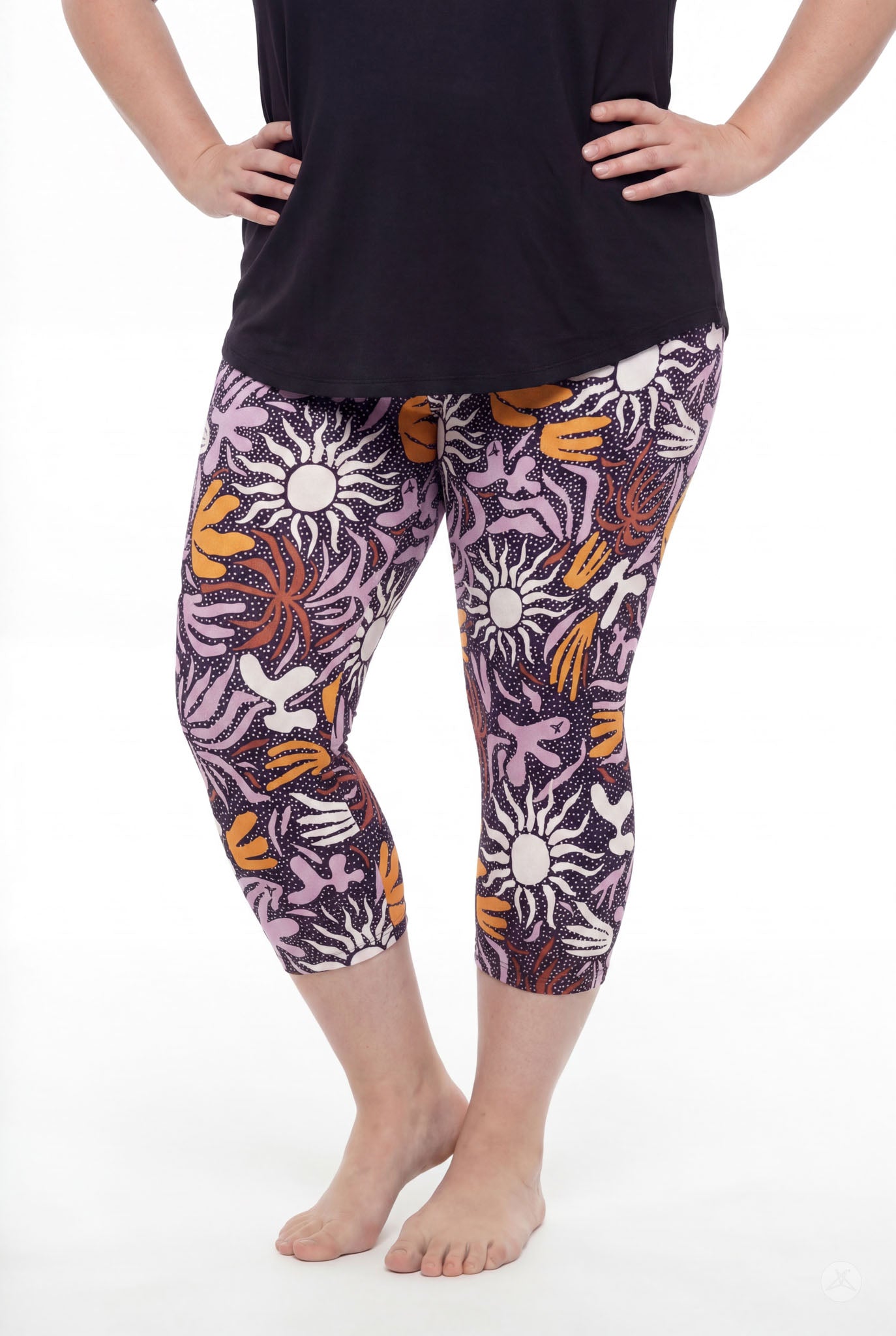 Curvy model wearing SweetLegs Retro Petals Crops with vibrant floral pattern and black top standing barefoot with hands on hips
