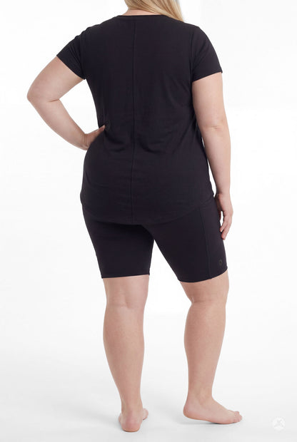 Plus size woman standing barefoot wearing SweetLegs Black Pocket Biker Shorts with a black short sleeve top rear view