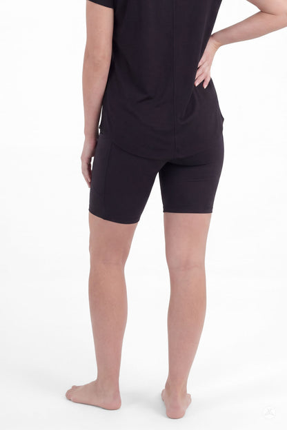 Woman wearing SweetLegs Black Pocket Biker Shorts standing barefoot with black top rear view