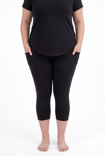 Woman wearing SweetLegs Black Pocket Crops with side pockets and black top standing barefoot facing forward