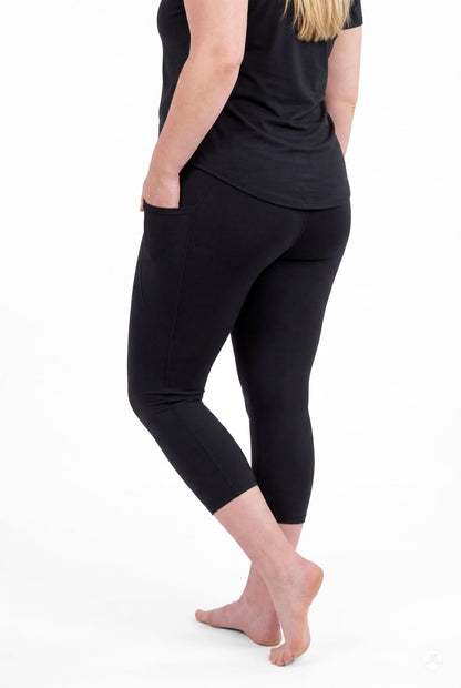 Woman standing barefoot showing back view wearing SweetLegs Black Pocket Crops with pockets and black top