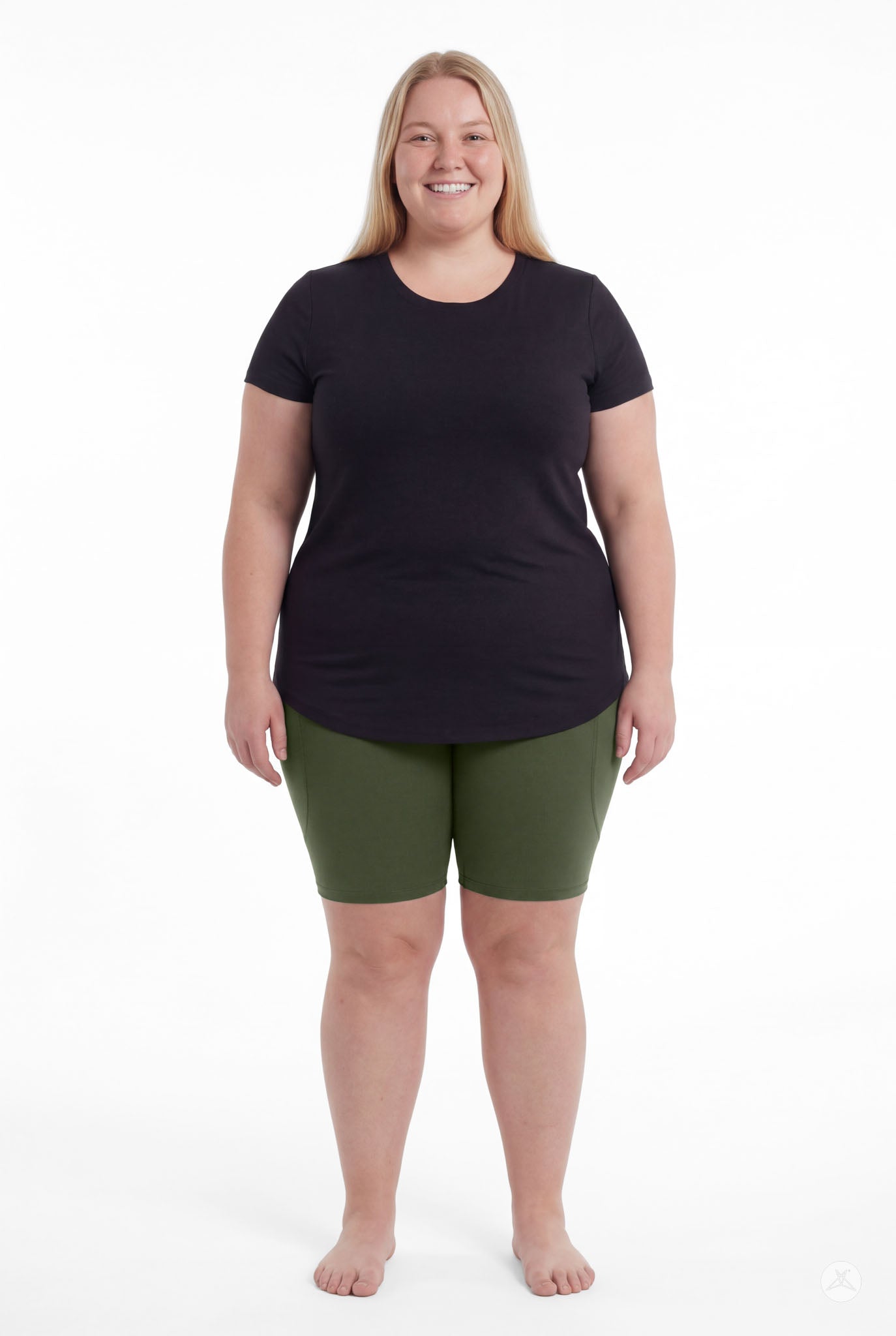 Smiling woman wearing SweetLegs Cedar Pocket Biker Shorts in green and black top standing barefoot front view