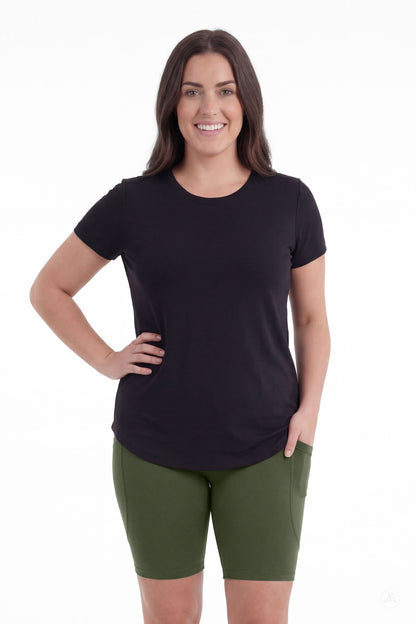 Smiling woman standing with hand in pocket wearing SweetLegs Cedar Pocket Biker Shorts in green and black top front view