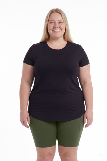 Smiling plus size woman wearing SweetLegs Cedar Pocket Biker Shorts in green with black t-shirt standing front view