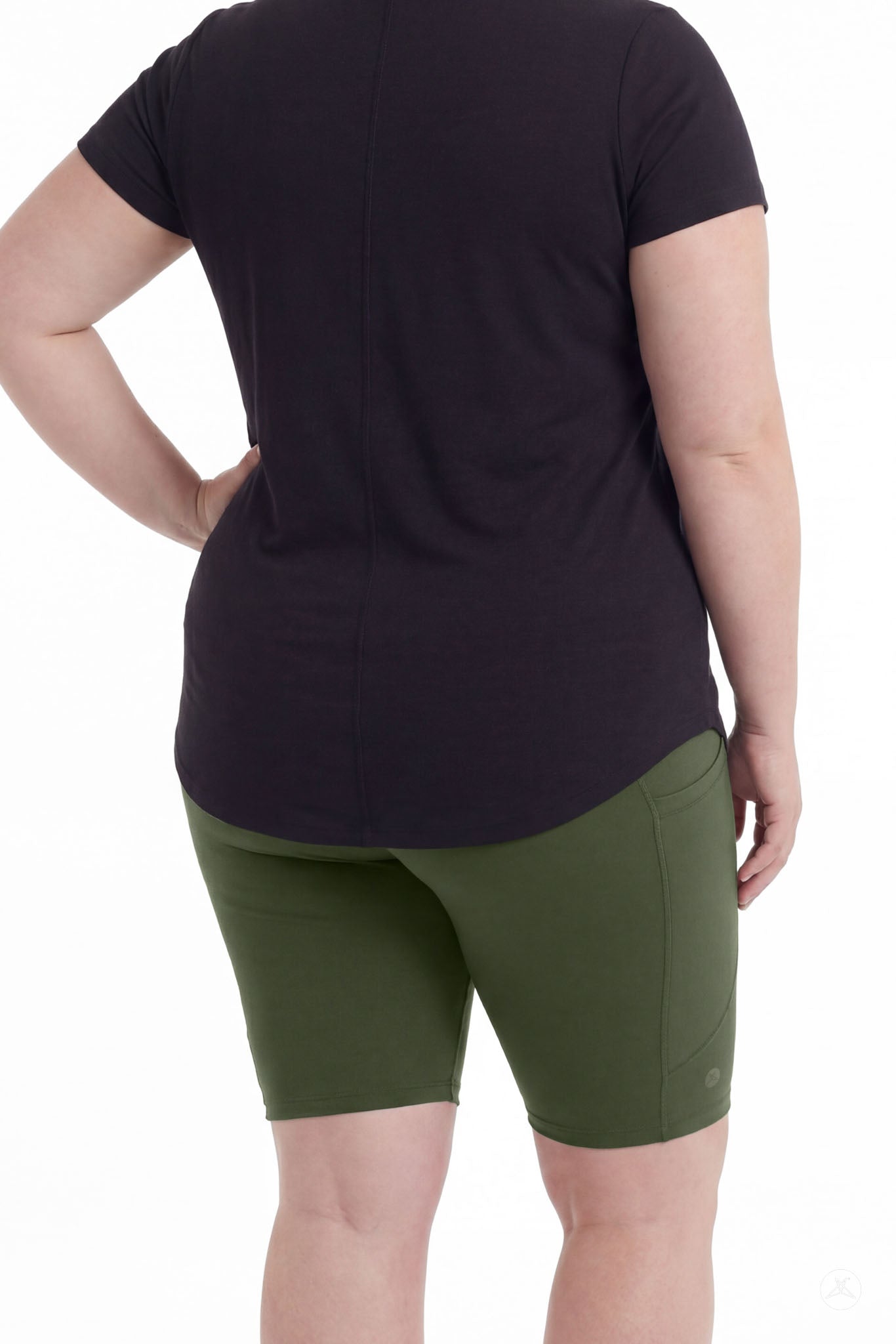 Plus size woman wearing SweetLegs Cedar Pocket Biker Shorts in green with black top standing rear view