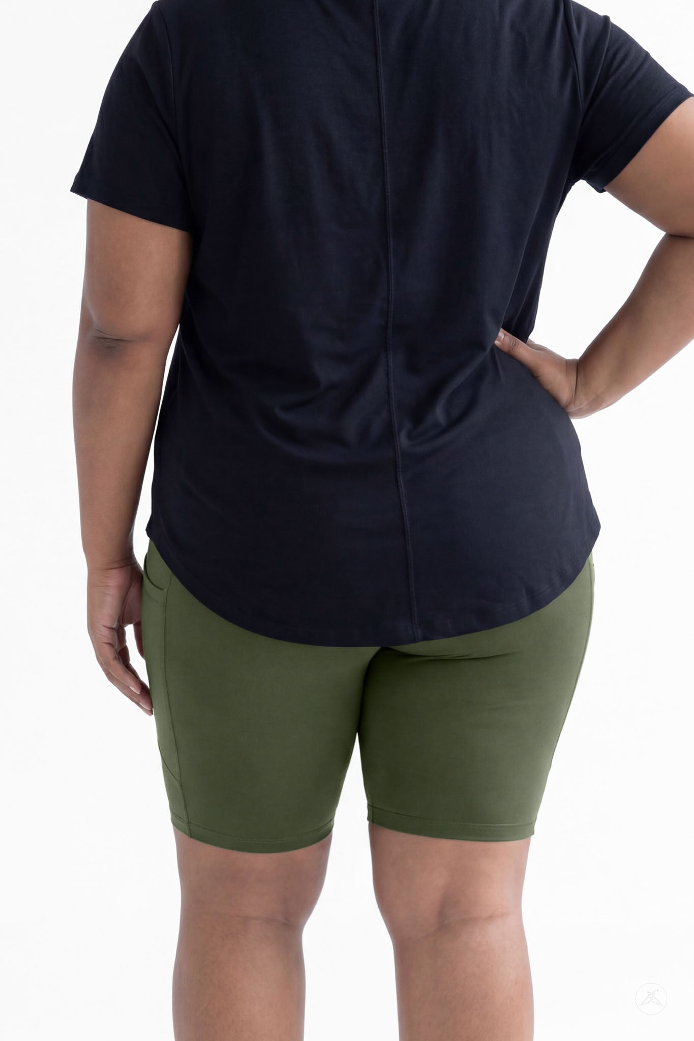 Plus size woman wearing SweetLegs Cedar Pocket Biker Shorts in green standing with hand on hip back view