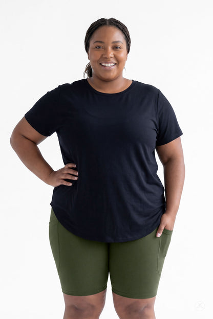 Smiling plus size woman wearing SweetLegs Cedar Pocket Biker Shorts in green with hand resting on hip front view