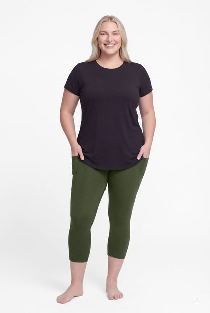 Smiling woman wearing SweetLegs Cedar Pocket Crops in green with side pockets and black short sleeve top barefoot