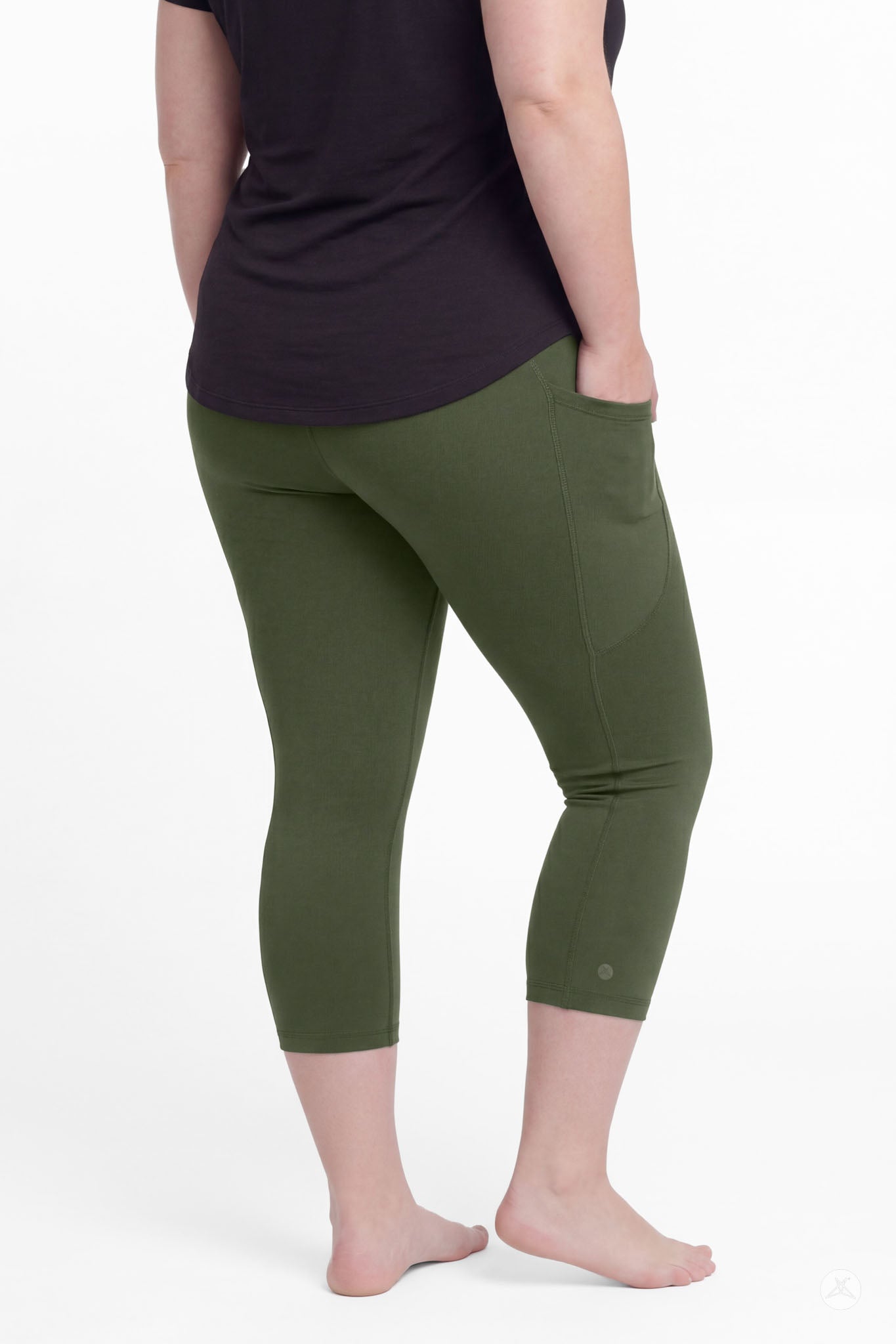 Plus size woman wearing SweetLegs Cedar Pocket Crops in olive green with side pockets and black top barefoot from back view