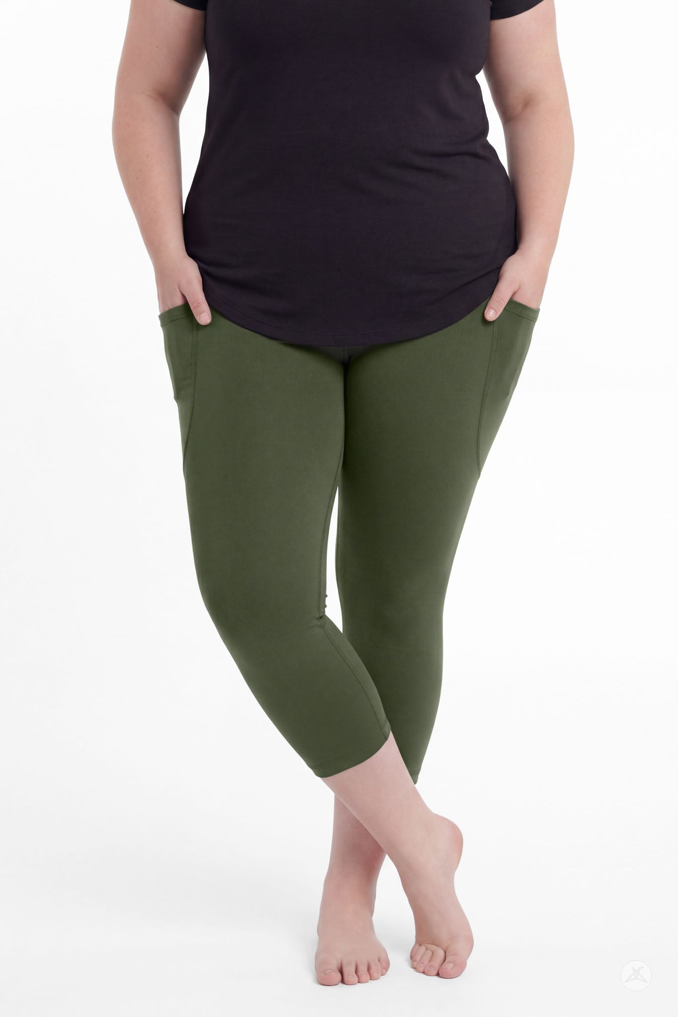 Plus size model wearing SweetLegs Cedar Pocket Crops in olive green with hands in pockets and black top barefoot
