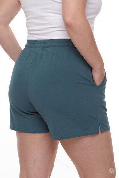 Rear view of person wearing teal Lounge Shorts by SweetLegs with elastic waistband, pockets, and small side slit